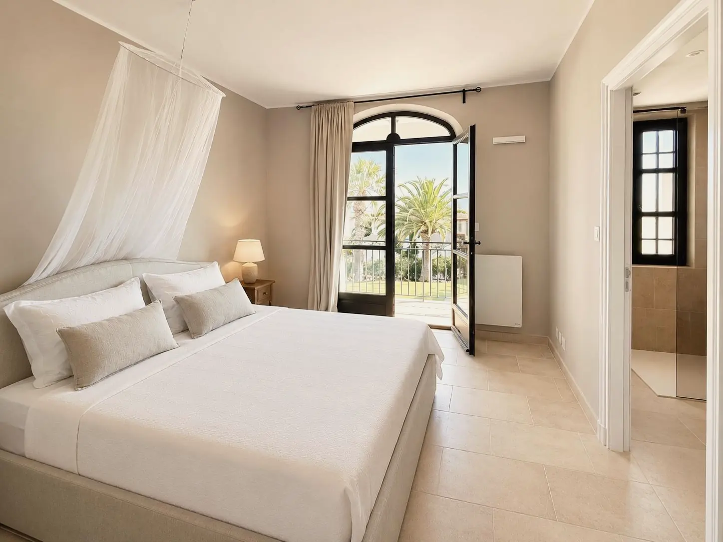 Dormitorio con cama con dosel de lino y puertas acristaladas en arco que dan al jardín